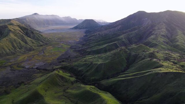 Aerial view of the majestic Mount Bromo landscape, showing stark contrasts between the lush green slopes and the volcanic caldera, Bromo Tengger Semeru National Park, East Java, Indonesia.