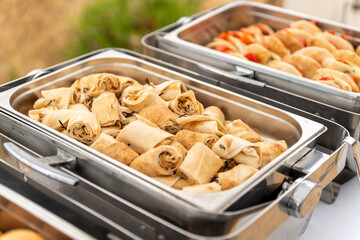 Delicious variety of rolled pastries served at an outdoor buffet during a sunny afternoon gathering