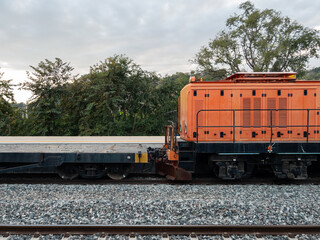 Orange Locomotive with Empty Container Cars at Station.
