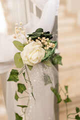 A beautiful floral decoration is attached to a wedding venue railing. It features white roses, greenery, and delicate accents