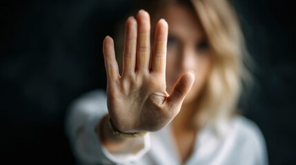 In a calm indoor environment, a woman raises her hand to signal stop as she addresses harassment, visibly expressing defiance and courage against inappropriate behavior