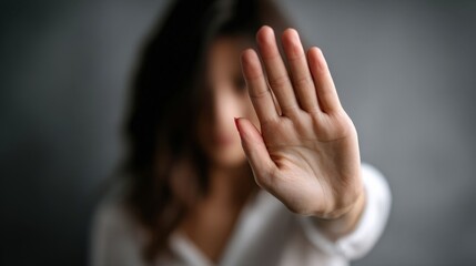 Obraz premium A woman holds up their hand to signal stop. Harassment at work. The setting appears dark, reflecting a serious atmosphere