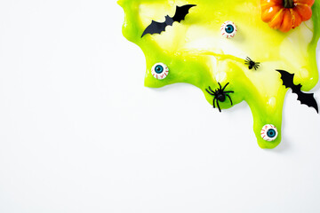 Bright green Halloween slime with eyeballs, spiders, bats, and a pumpkin on white background.