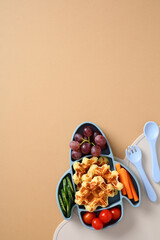 Creative rocket-shaped plate with waffles, grapes, cucumbers, carrots, tomatoes. Fun and healthy food layout for kids nutrition