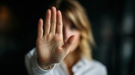 In a calm indoor environment, a woman raises her hand to signal stop as she addresses harassment, visibly expressing defiance and courage against inappropriate behavior