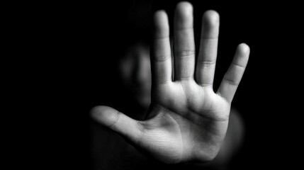 Fototapeta premium A person stands defiantly in a dark environment, raising their hand to signal a boundary while conveying a powerful message against harassment. The focus is on their determined expression