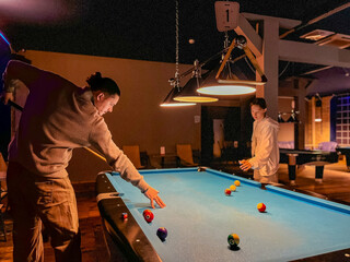 Father and his teenager daughter play billiards. The father teaches his son to play billiards. The concept of parents and children, upbringing, family rest.