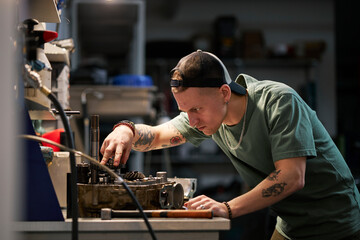 Mechanic repairing machine part at workshop table focusing on detail