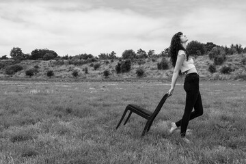 Young woman carrying chair in field