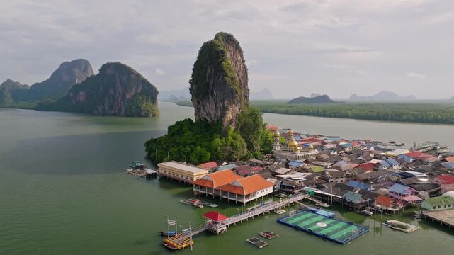 Aerial view of Ko Panyi, a village built on stilts, contrasts the natural rock formations with colorful buildings and a floating football field, Ko Panyi, Phang Nga, Thailand.