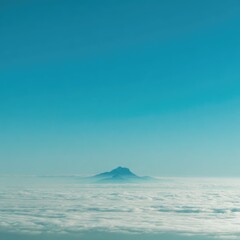 Mountain peak above a vast sea of clouds, vibrant blue sky