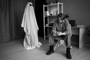 Concept of afterlife and memory for lost love. Depressed sad widower crying holding old photo while...