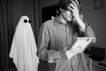afterlife and memory of lost love. Widower man cries looking at old photo ghost of wife standing...