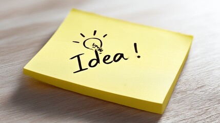 Close-up yellow Post-it note with handwritten 'Idea!' and a lightbulb icon.