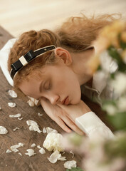 Serene young woman resting among flower petals.