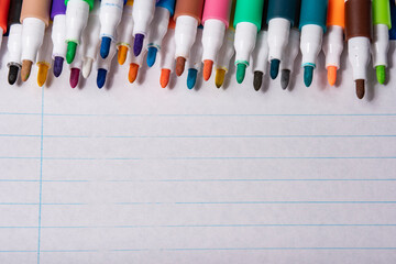 Juego de rotuladores multicolores sobre hoja de papel con rallas