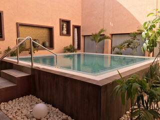 Luxury Spa Plunge Pool with Wooden Decking and Terracotta Walls Surrounded by Greenery