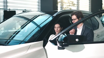 Car dealership scene featuring a man and woman discussing vehicle features inside a modern car, showcasing customer engagement and sales interaction