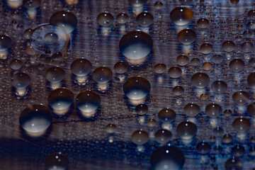 Condensation from water droplets of various sizes on opaque dark glass, macro photograph
