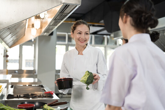Group of young female chef wearing white apron during preparing food and learning cooking in kitchen