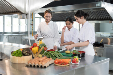 Group of young female chef wearing white apron during preparing food and learning cooking in kitchen