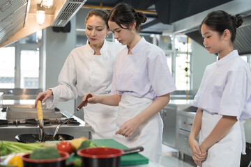 Group of young female chef wearing white apron during preparing food and learning cooking in kitchen