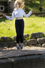 Young girl jumping with skipping rope in park