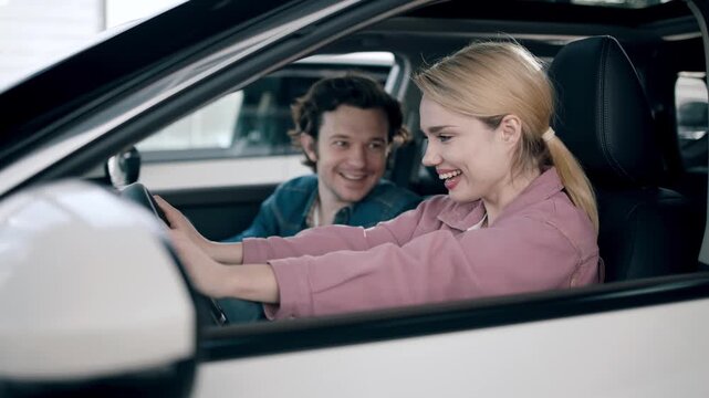Young couple enjoying test drive experience in a modern car dealership, showcasing excitement and connection during the car buying process