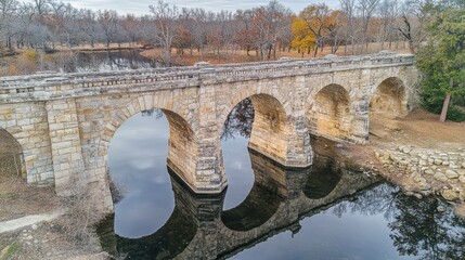 Bridge structural symmetry historic stone arch aerial view multiple arches reflected calm water natural background green foliage