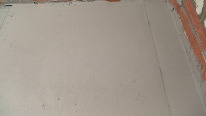 Workers applying self-leveling concrete on construction site floor