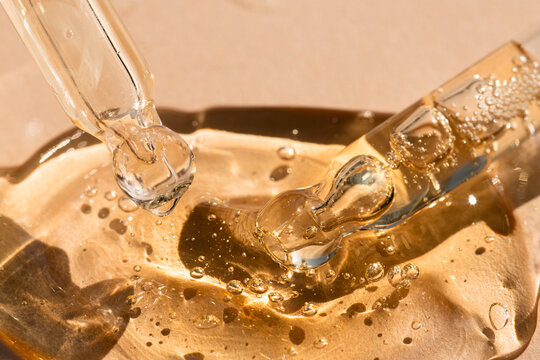 Glass skin care tools with gel, oil, essence beige background, macro.