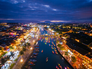 Fototapeta premium Vibrant night scene of Hoi An with lantern boats with tourist on thu bon river, aerial view landscape of Vietnam