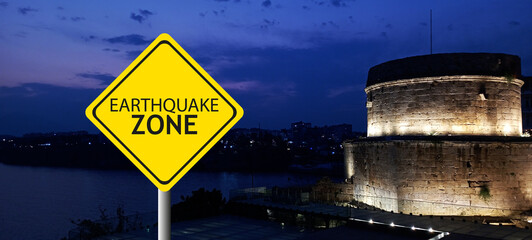 Caution Earthquake Zone Sign on Cracked Rock Background