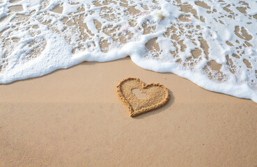 Heart shape drawn in sand by ocean waves on a beach  