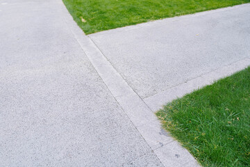 roadside of an concrete road with a stone curb in the background lawn with green grass