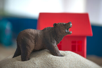 The concept of psychology. Sand
therapy. A bear figurine on
the background of a red house, in a blue
sandbox. Psychology. Therapy.