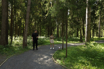 Man and young woman stroll through a pine forest with their pet dog, bonding through a peaceful weekend walk in the woods