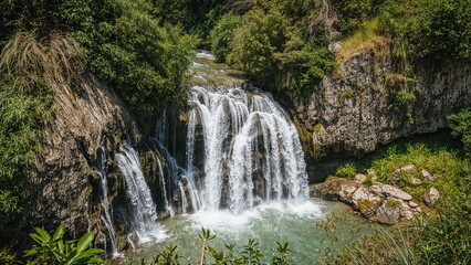 Fototapeta premium Stunning water descent over jagged cliffs embraced by rich natural foliage