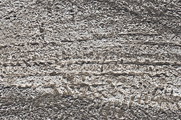 Tire tracks in dry concrete texture. Rough surface with pattern. Grunge detail of old road imprint....