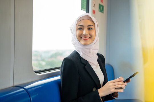 Muslim asian woman using smartphone while travel by train station in the city. Beautiful islamic female checking application on cell phone