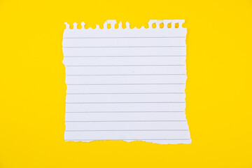White ripped lined paper sheet isolated on vibrant yellow background for note-taking, reminders, or educational purposes