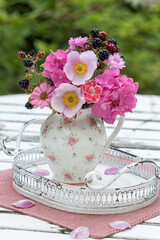Blumenstrauß mit pink Hortensienblüten, Herbst-Anemonen, Nelken und Zinnie im Porzellan-Kännchen im Garten