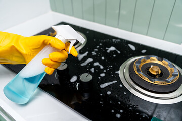 Hand woman cleaning the gas stove with sponge. Housekeeper cleaning kitchen