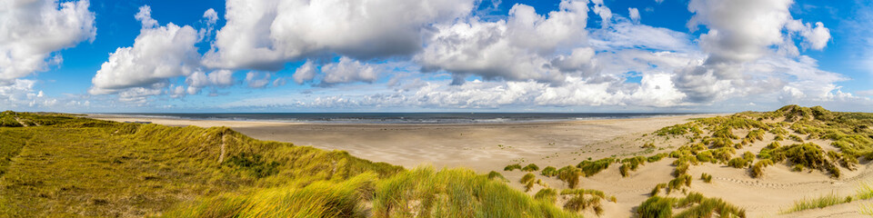 A panoramic photo of the Oosterend Beach on the island of Terschelling with a beautiful Dutch cloudy sky above the sea