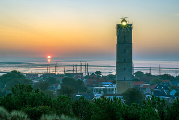 The Brandaris lighthouse on Terschelling just spreads its last rays of light as the sun rises above...