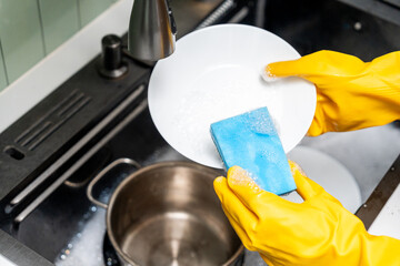 Close up woman hand washing plate. Female housekeeper cleaning some dish plate after dining....
