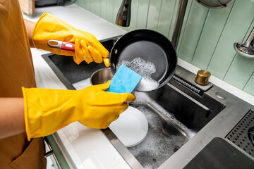 Close up woman hand washing pan. Female housekeeper cleaning pan after cooking. Housework Cleaning...