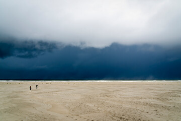 Two people venture onto Oosterend Beach, Terschelling, while a huge rain shower almost turns the...