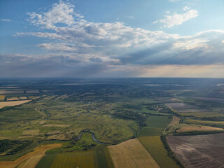 Green pastures and agricultural fields captured from above under a moody sky ready for rainfall.