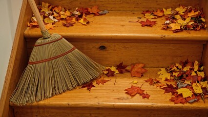 Straw Broom Leaning Against Steps with Seasonal Leaves